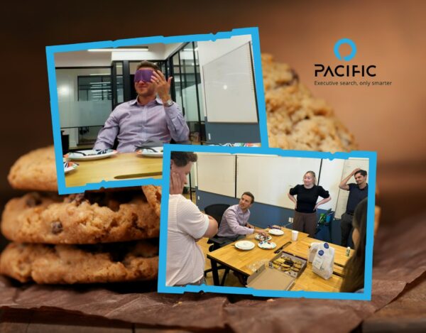 Two office workers participate in a blindfolded taste test, while others observe in a meeting room with biscuits and the Pacific company logo in the background.
