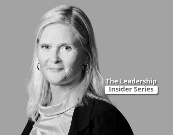 A woman with fair hair wearing a jacket and blouse stands in front of a grey background with the text "The Leadership Insider Series.