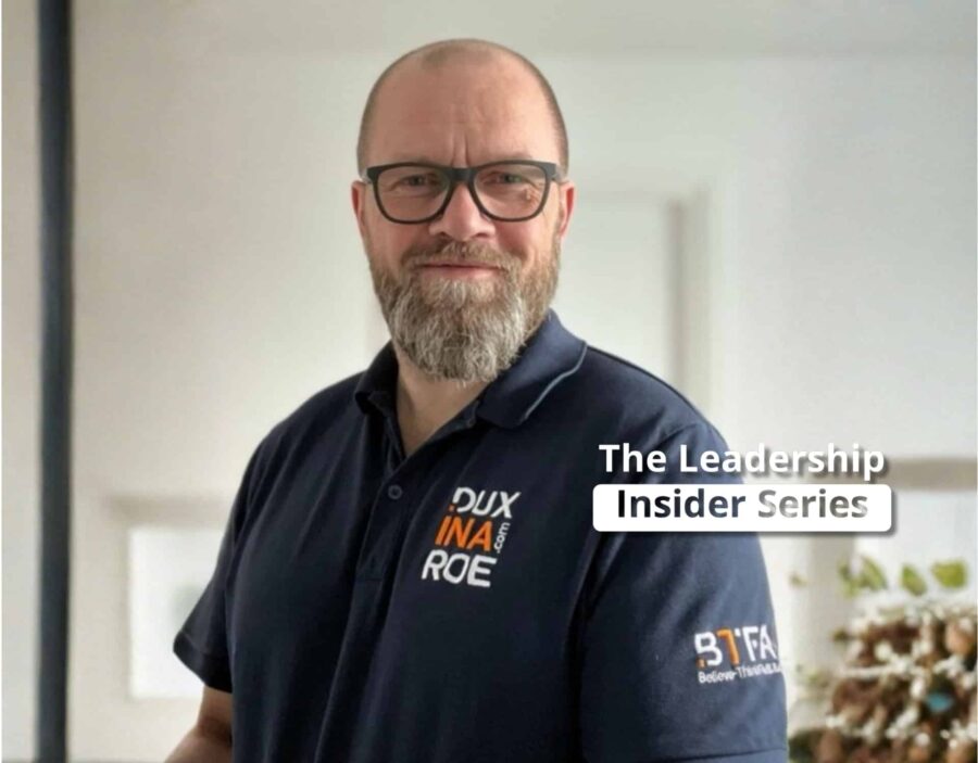 Ein Mann mit Brille und Bart, der ein Marken-Poloshirt trägt, steht in einem Haus. Der Text lautet: "Die Leadership Insider Series - Einblicke in die Schnittmenge von Führung und Neurowissenschaften.
