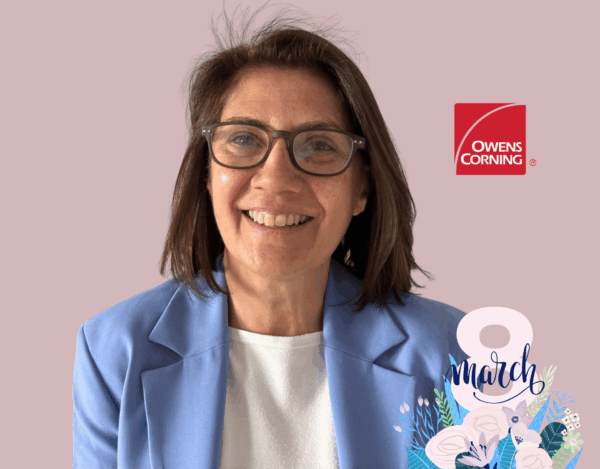 Smiling woman with glasses in a light blue blazer, Owens Corning logo on the right, and a “8 March” floral graphic in the bottom corner.